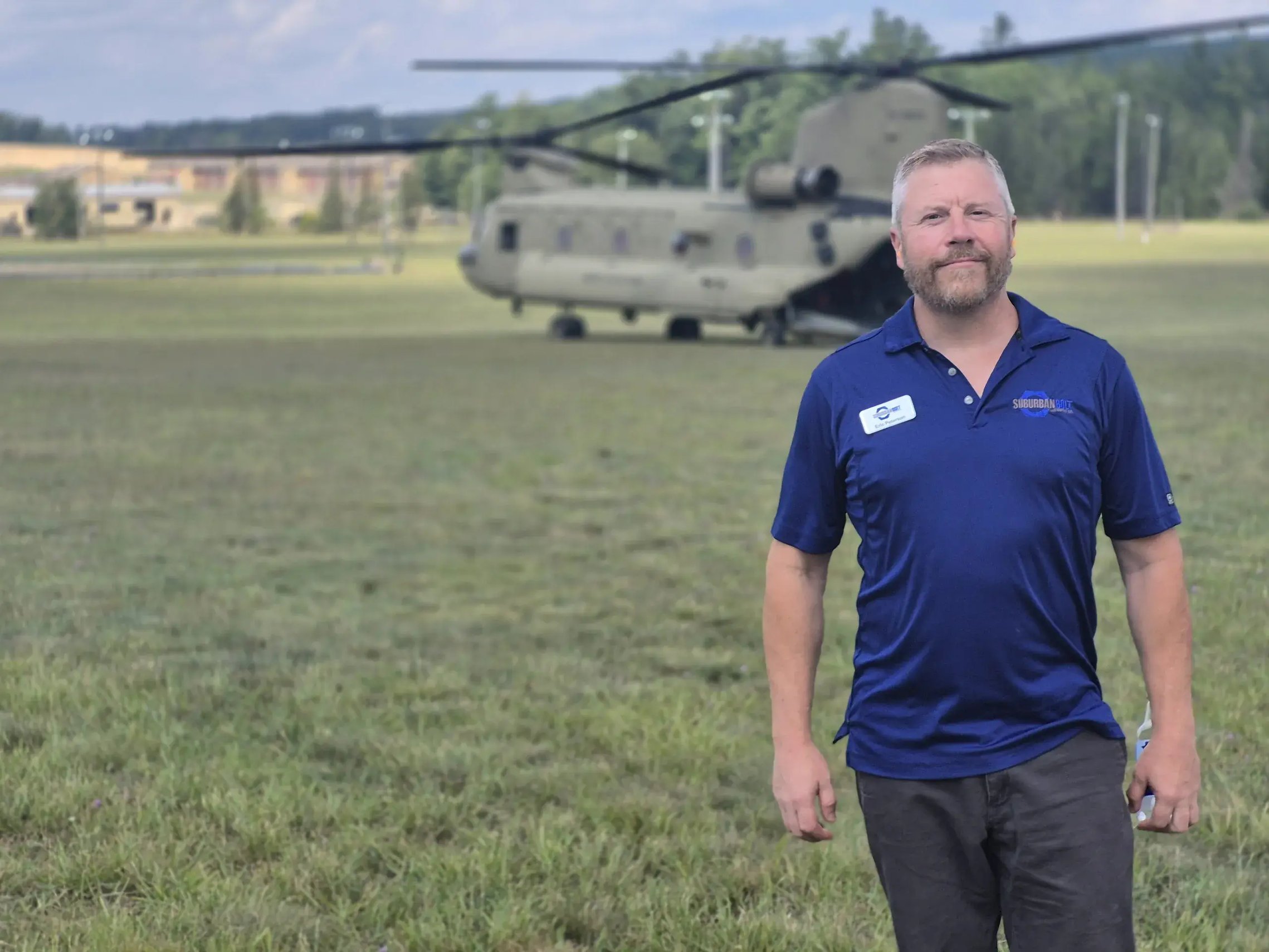 Eric Peterson of Suburban Bolt standing in front of a Chinook helicopter at Camp Grayling