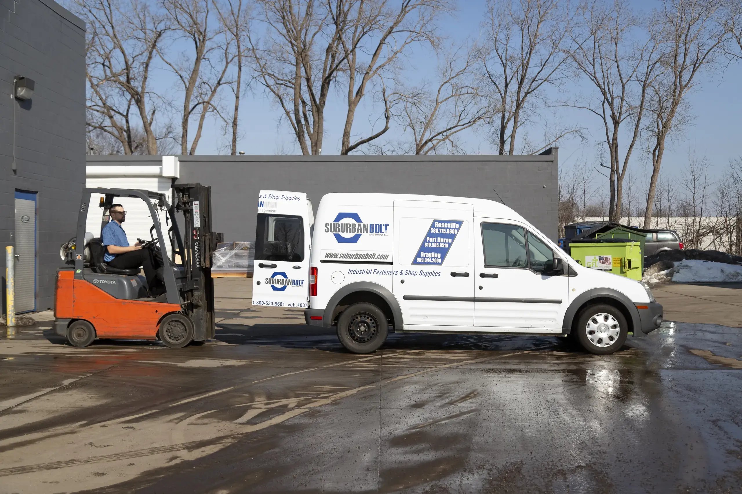 Forklift loading a Suburban Bolt delivery van outside the warehouse
