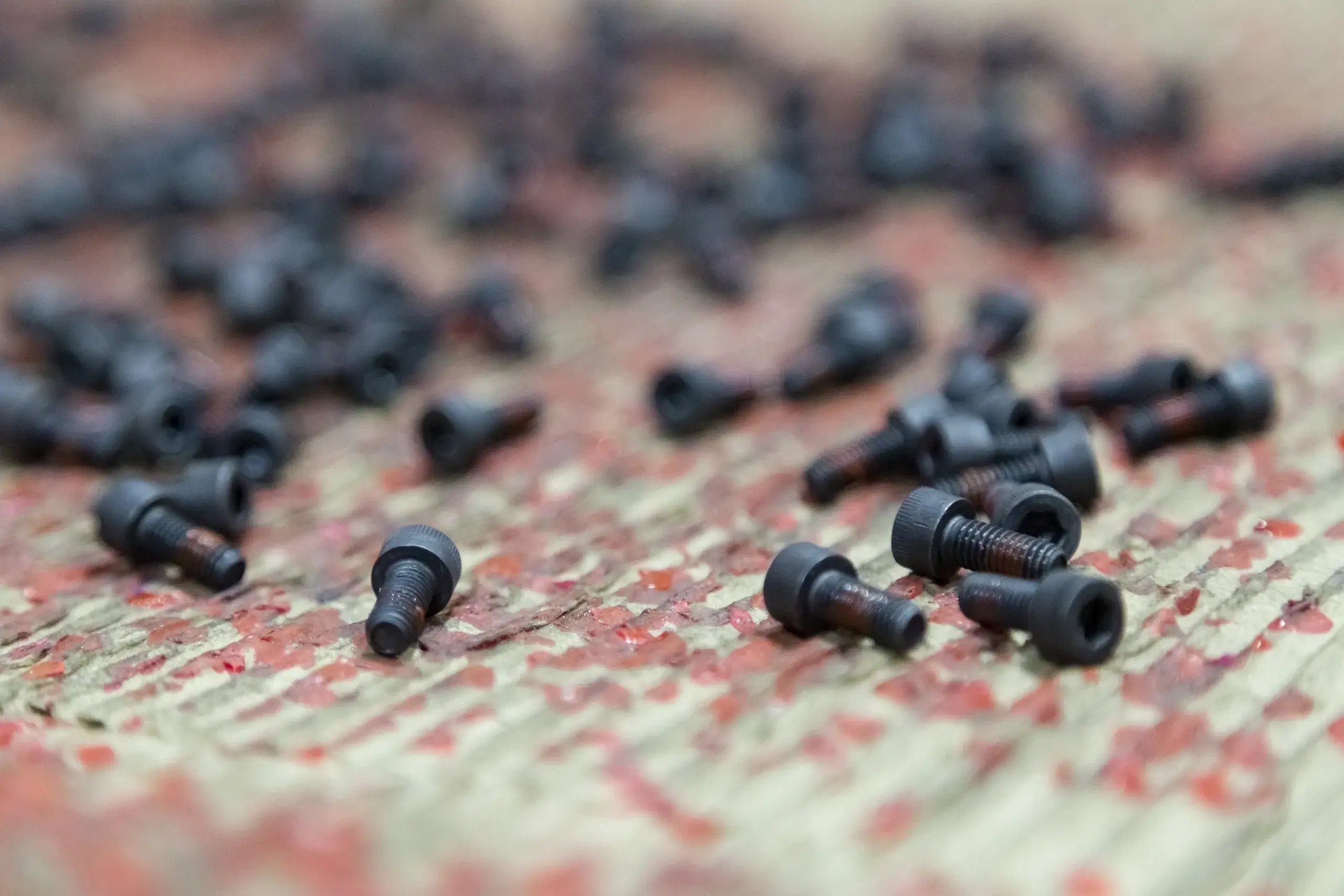Close-up of black socket head cap screws with red thread locker