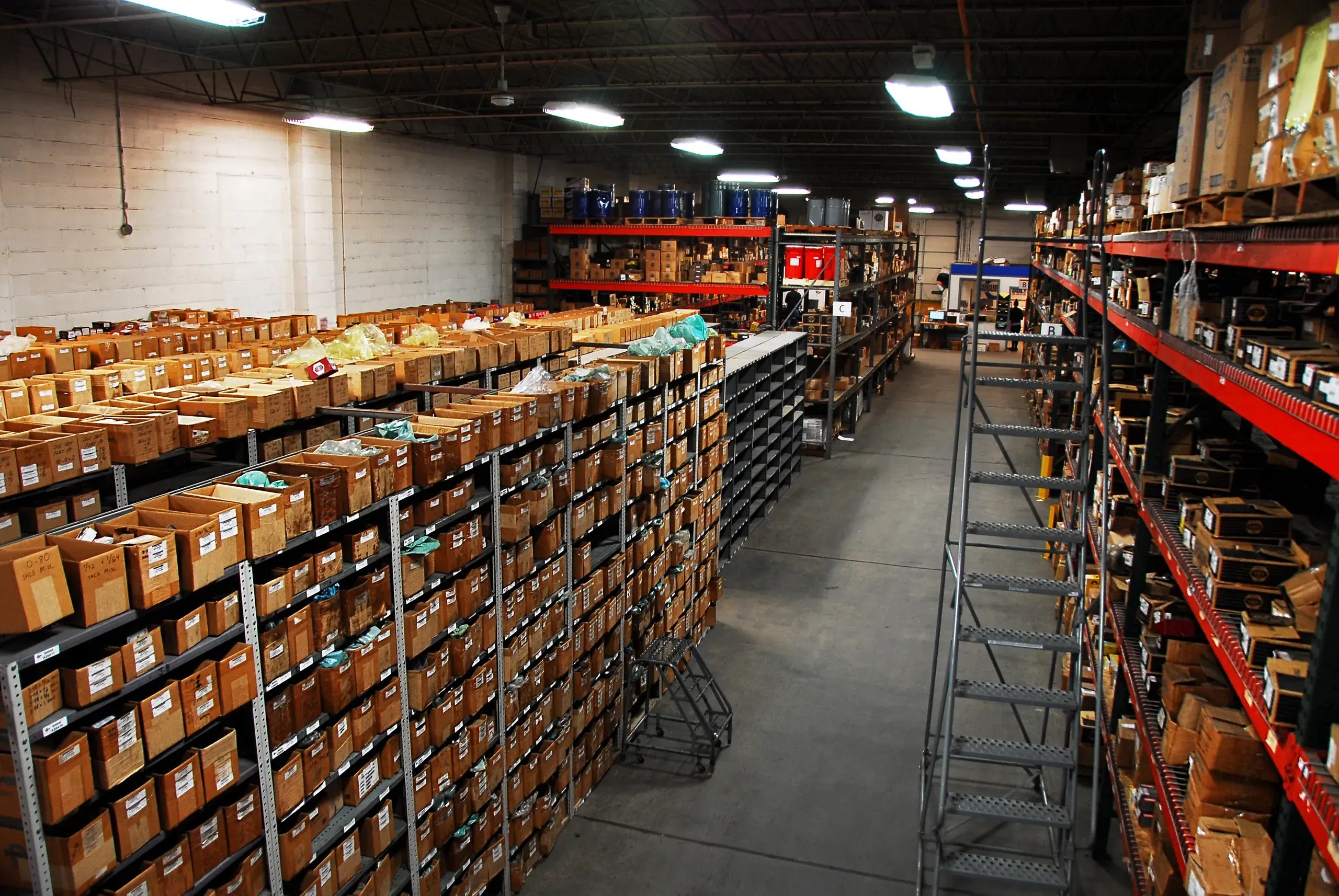 Overhead view of boxed fastener bin shelving and a rolling ladder in the warehouse
